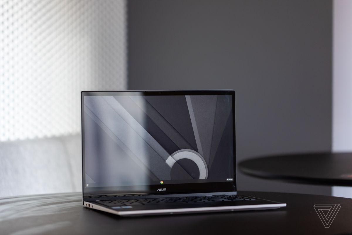 Das Asus Chromebook CX5 offen, nach rechts geneigt, auf einem Tisch mit grau-weißem Hintergrund.  Der Bildschirm zeigt ein schwarz-weiß-graues Desktop-Muster an.